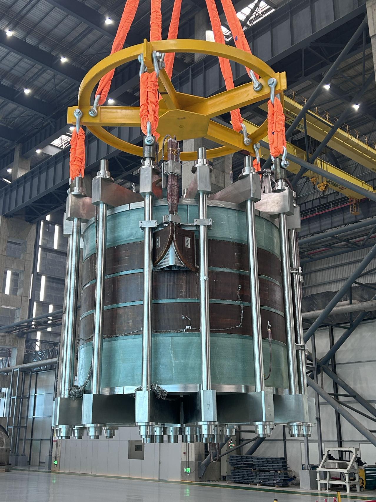 A fusion-reactor superconducting magnet being hoisted inside a workshop